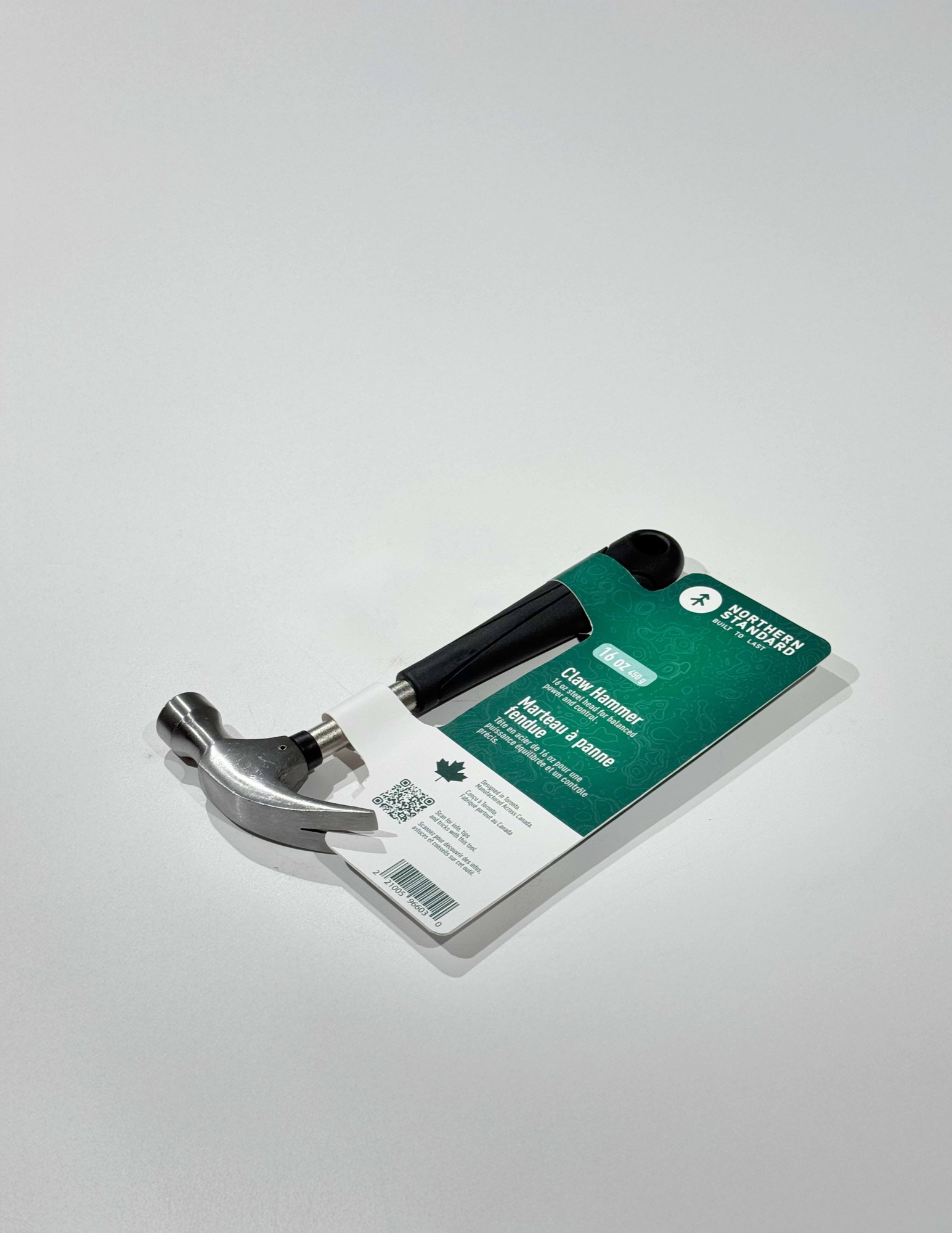 Northern Standard claw hammer prototype on an off-white studio surface, with green bilingual packaging card attached